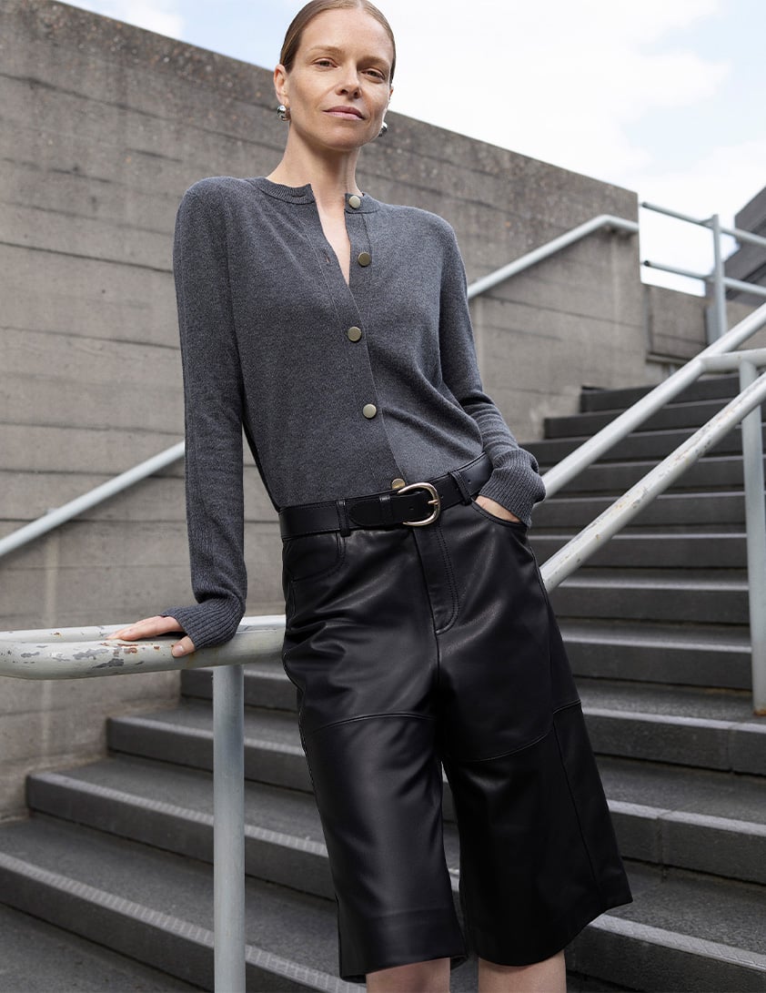 Woman wearing Whistles grey military style buttoned cardigan with black leather shorts
