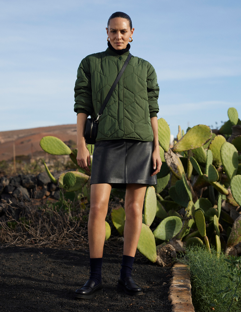 Woman wearing green qulited short jacket and leather mini skirt