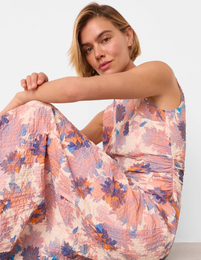 Woman wearing a sleeveless textured floral midi dress in pink and purple tones for Whistles 25% percent off everything labor day promotion