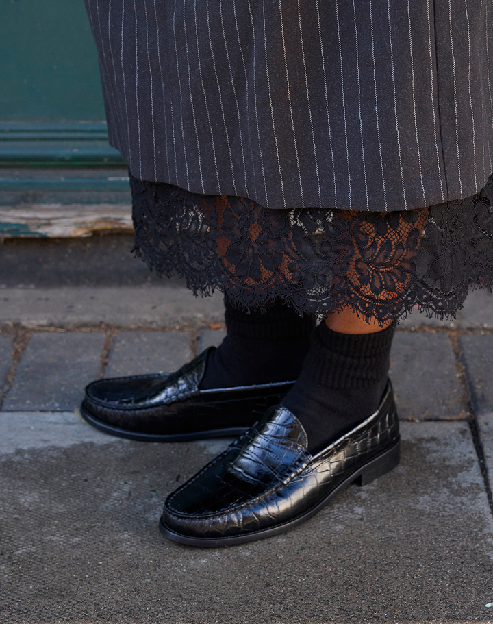 Black leather loafers styled with a lace-trim skirt