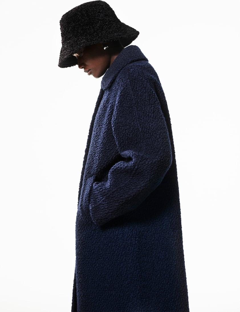 Woman wearing a Whistles navy textured wool coat paired with a black boucle bucket hat.